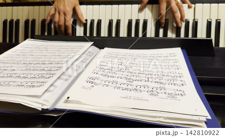 Top view of adult female hands playing gentle piece of classical music on black piano. Scene captures the movement, rhythm and elegance of performance, highlighting beauty of live instrumental play Top view of adult female hands playing gentle piece of classical music on black piano. Scene captures the movement, rhythm and elegance of performance, highlighting beauty of live instrumental play 142810922