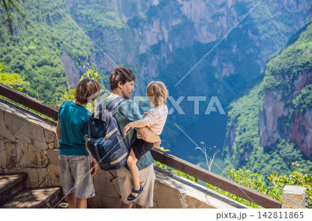 Father with two sons admiring Sumidero Canyon and the river below in Chiapas Mexico with steep canyon walls lush landscape river overlook nature tourism and exploring the canyon viewpoint. 142811865