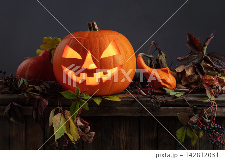 Halloween pumpkin head jack lantern with dried-up leaves. Halloween pumpkin head jack lantern with dried-up leaves. 142812031