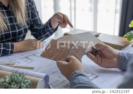 Architect and Interior Designer Collaborating on Floor Plans with Wood Samples. Architect and Interior Designer Collaborating on Floor Plans with Wood Samples. 142812197