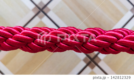 Red Braided Stanchion Rope Closeup with Parquet Flooring Background in Historical Interior 142812329