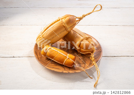 Provolone cheese, some smoked provolone cheeses made in Brazil placed on a ceramic plate, on rustic white wood, selective focus. Provolone cheese, some smoked provolone cheeses made in Brazil placed on a ceramic plate, on rustic white wood, selective focus. 142812866