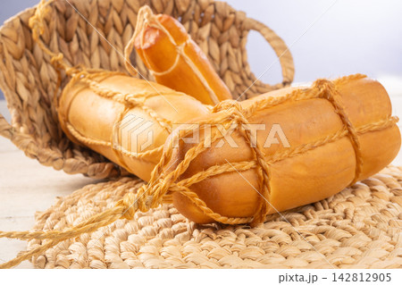 Provolone cheese, Some smoked provolone cheeses made in Brazil placed on straw utensils, on rustic white wood, selective focus. 142812905