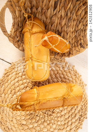 Provolone cheese, Some smoked provolone cheeses made in Brazil placed on straw utensils, on rustic white wood, selective focus. 142812908