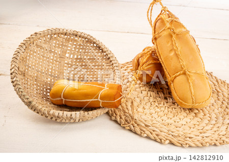 Provolone cheese, Some smoked provolone cheeses made in Brazil placed on straw utensils, on rustic white wood, selective focus. 142812910