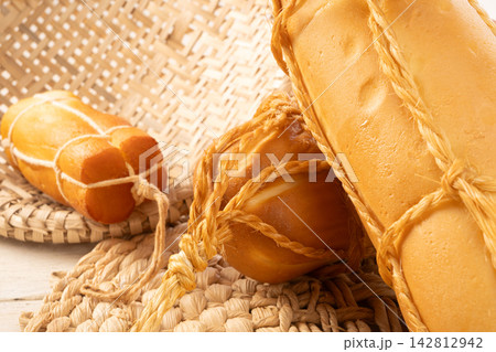 Provolone cheese, Some smoked provolone cheeses made in Brazil placed on straw utensils, on rustic white wood, selective focus. Provolone cheese, Some smoked provolone cheeses made in Brazil placed on straw utensils, on rustic white wood, selective focus. 142812942
