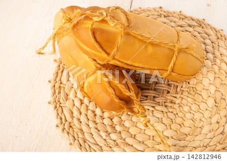 Provolone cheese, Some smoked provolone cheeses made in Brazil placed on straw utensils, on rustic white wood, selective focus. 142812946