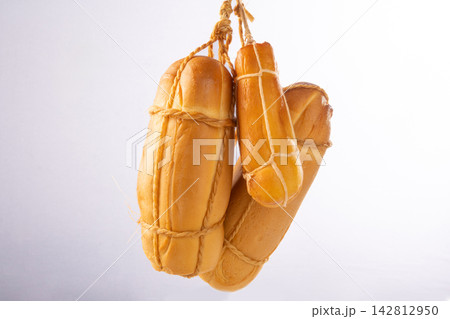 Provolone cheese, some smoked provolone cheeses made in Brazil hanging from ropes, white background, selective focus. Provolone cheese, some smoked provolone cheeses made in Brazil hanging from ropes, white background, selective focus. 142812950