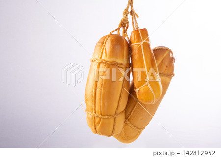 Provolone cheese, some smoked provolone cheeses made in Brazil hanging from ropes, white background, selective focus. Provolone cheese, some smoked provolone cheeses made in Brazil hanging from ropes, white background, selective focus. 142812952
