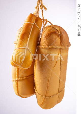 Provolone cheese, some smoked provolone cheeses made in Brazil hanging from ropes, white background, selective focus. 142812958