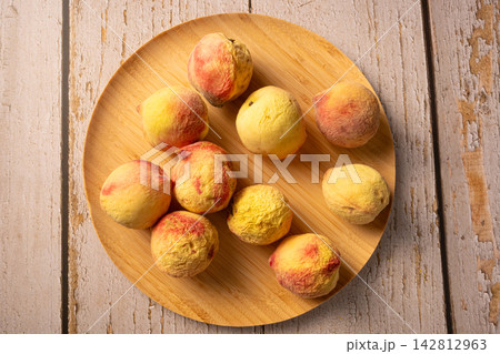 Old peaches, some old peaches in a rustic bowl on a rustic wooden table, selective focus. Old peaches, some old peaches in a rustic bowl on a rustic wooden table, selective focus. 142812963