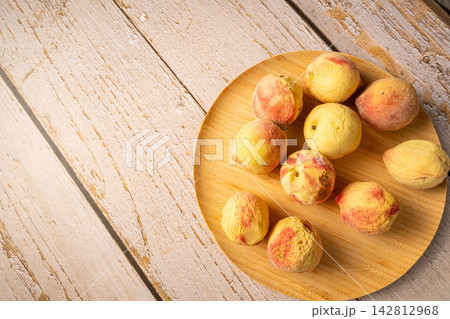 Old peaches, some old peaches in a rustic bowl on a rustic wooden table, selective focus. 142812968