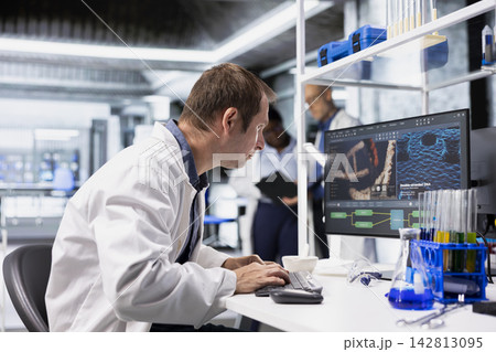 Chemist in biolab observes computer with fascination and curiosity, captivating experiment data results. Intrigued scientist reading compelling unusual biotechnology research discovery. 142813095