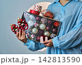 Woman holding box of christmas decorations and gift 142813590