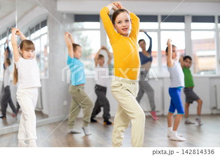 Girl learn to dance modern dances, doing movement with unrecognizable teacher. 142814336