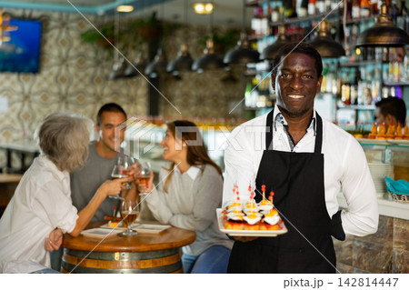 View on the African adult man holding pinchos at a bar 142814447