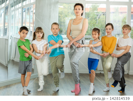 Smiling preteen children learning to dancing folk dance in row in studio Smiling preteen children learning to dancing folk dance in row in studio 142814539