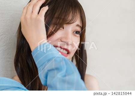 髪に手を添えて明るい笑顔を見せる女性。自然な表情とヘアスタイルの美容イメージ 髪に手を添えて明るい笑顔を見せる女性。自然な表情とヘアスタイルの美容イメージ 142815044