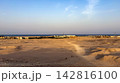 Arid desert landscape leading to a coastal town and sea horizon 142816100