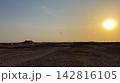 Airplane flying over vast desert landscape at sunset 142816105