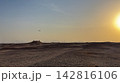 Airplane flying over a sandy desert landscape at sunset 142816106