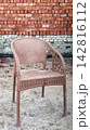 Brown plastic armchair standing against a red brick wall 142816112