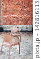 Two plastic chairs standing in an unfinished room with brick wall 142816113