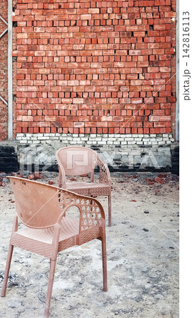 Two plastic chairs standing in an unfinished room with brick wall Two plastic chairs standing in an unfinished room with brick wall 142816113