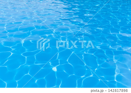 Clear blue water surface of a swimming pool reflects sunlight, featuring gentle ripples and patterns that create a serene aquatic environment Clear blue water surface of a swimming pool reflects sunlight, featuring gentle ripples and patterns that create a serene aquatic environment 142817898