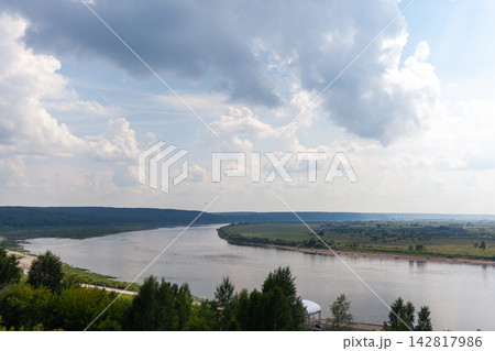 Winding river flows through a green landscape with hills and trees under a cloudy sky, creating a serene and picturesque outdoor scene Winding river flows through a green landscape with hills and trees under a cloudy sky, creating a serene and picturesque outdoor scene 142817986