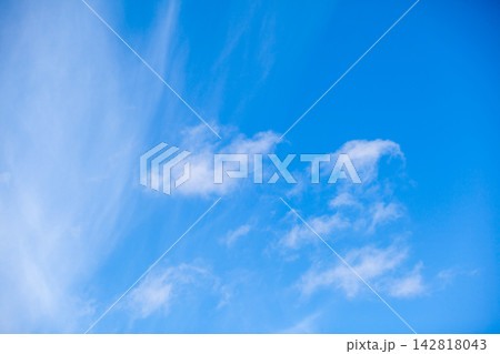 Clear blue sky featuring white clouds scattered throughout, with wispy formations adding texture to the serene daytime scene 142818043