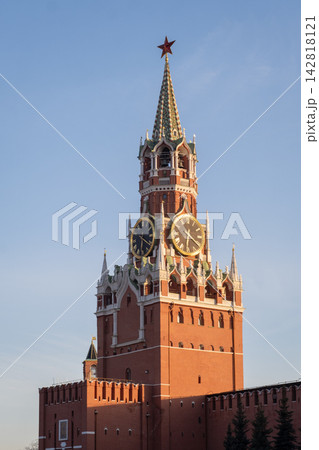 Red Square clock tower features a star-topped spire and prominent clock faces, set against a bright blue sky in Moscow, Russia 142818121