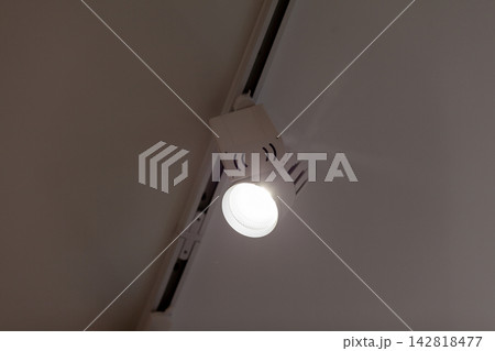 Track lighting fixture features an adjustable spotlight directed at the ceiling in a contemporary interior, highlighting modern design elements Track lighting fixture features an adjustable spotlight directed at the ceiling in a contemporary interior, highlighting modern design elements 142818477