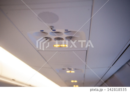 Airplane cabin ceiling features overhead lights and air vents, highlighting the modern design of aircraft interiors and passenger comfort features 142818535