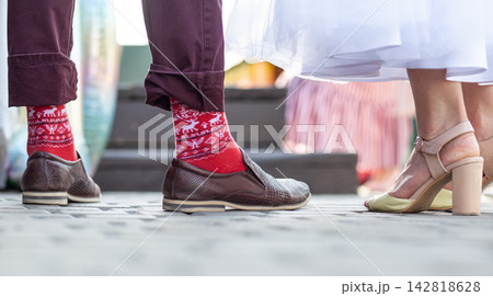 Man and woman in colorful socks and fashionable shoes stand close together on a cobblestone street, with blurred surroundings adding depth 142818628