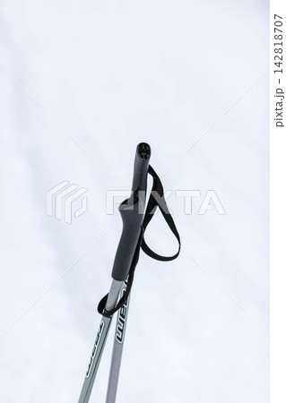 Close-up view of a black ski pole grip featuring a strap, set against a soft, white snowy background, emphasizing winter sports gear Close-up view of a black ski pole grip featuring a strap, set against a soft, white snowy background, emphasizing winter sports gear 142818707