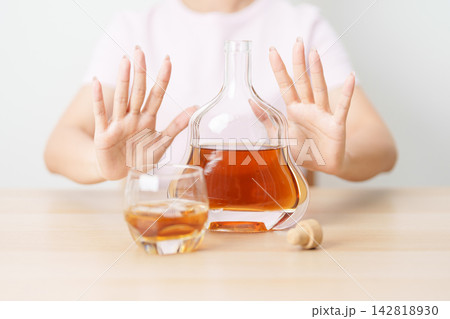 woman making stop hand gesture to refuse a glass of Cognac, Healthy man say no to alcohol drink, stop alcoholism and addiction concept. Responsible man reject a drink before driving and quit booze woman making stop hand gesture to refuse a glass of Cognac, Healthy man say no to alcohol drink, stop alcoholism and addiction concept. Responsible man reject a drink before driving and quit booze 142818930