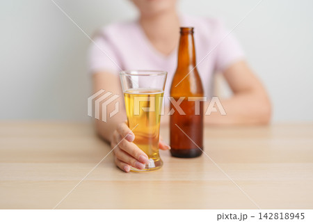 woman with glass of Beer on table, suffering from alcohol addiction and alcoholism concept. depicting emotional distress, depression, substance abuse problem, unhealthy lifestyle and mental health 142818945