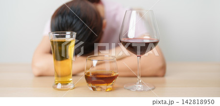 Stressed woman drinking wine, beer, whiskey or cognac alone with problem. Exhausted drunk woman looking stressed and sleepy. Alcohol addiction, Alcoholism, emotional distress and mental health 142818950