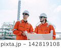 Refinery Engineers Holding Blueprint Discussion Outdoor Industrial Plant Complex Site. 142819108