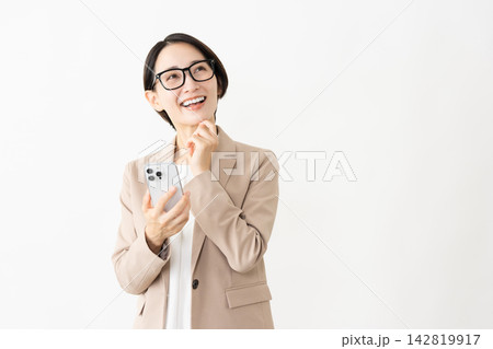 スマトフォンを使う眼鏡をかけたスーツ姿の女性 スマトフォンを使う眼鏡をかけたスーツ姿の女性 142819917