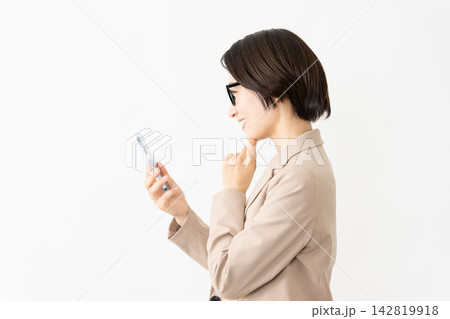 スマトフォンを使う眼鏡をかけたスーツ姿の女性 142819918