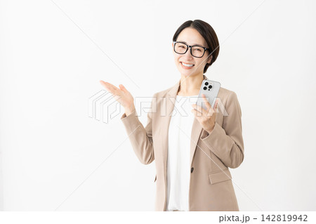 スマトフォンを使う眼鏡をかけたスーツ姿の女性 スマトフォンを使う眼鏡をかけたスーツ姿の女性 142819942