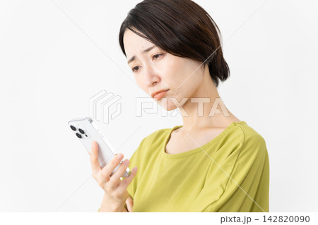 スマートフォンを使うカットソー姿の女性　ライフスタイルイメージ 142820090