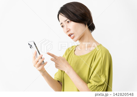 スマートフォンを使うカットソー姿の女性　ライフスタイルイメージ 142820548