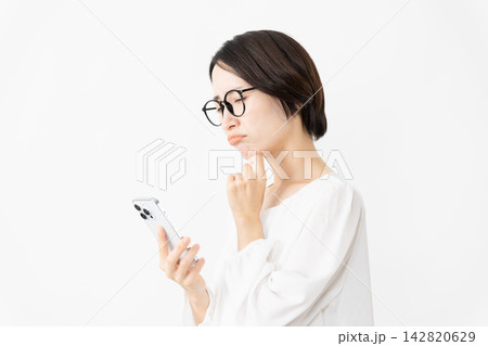 スマートフォンを使うメガネをかけたカットソー姿の女性　ライフスタイルイメージ 142820629