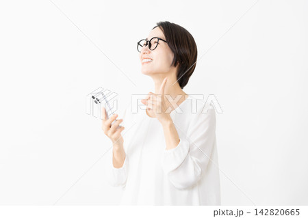 スマートフォンを使うメガネをかけたカットソー姿の女性　ライフスタイルイメージ 142820665