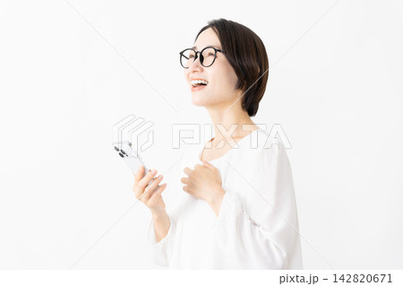 スマートフォンを使うメガネをかけたカットソー姿の女性　ライフスタイルイメージ 142820671