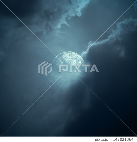 Full moon glowing through dramatic dark storm clouds in a moody blue night sky. Smoke background Full moon glowing through dramatic dark storm clouds in a moody blue night sky. Smoke background 142821364