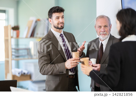 Coffee break - men and young woman drink coffee and chat lively with each other in modern office 142821856